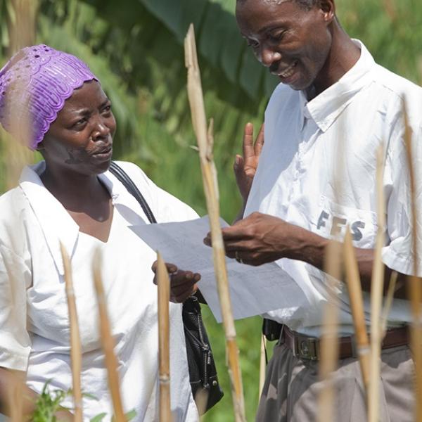 A man and a woman discussing a paper in the hands of the man in a rural area